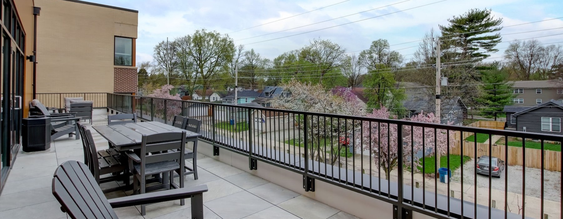 a deck with chairs and tables on it and trees in the back